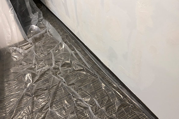 Drop cloth on floor during torn drywall paper repair
