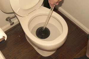 plunger in a clogged toilet that was overflowing