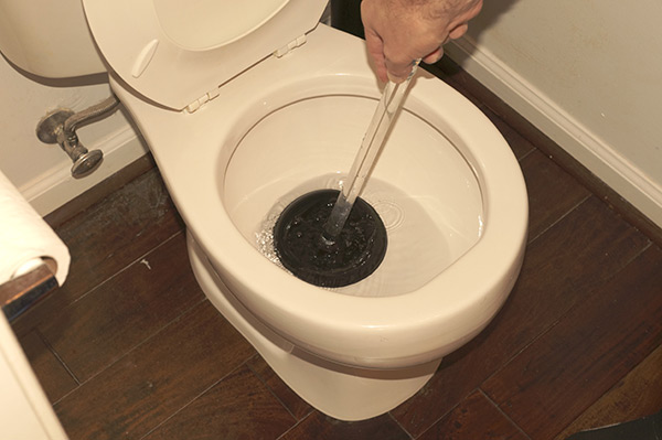 plunging a clogged toilet drain that was overflowing